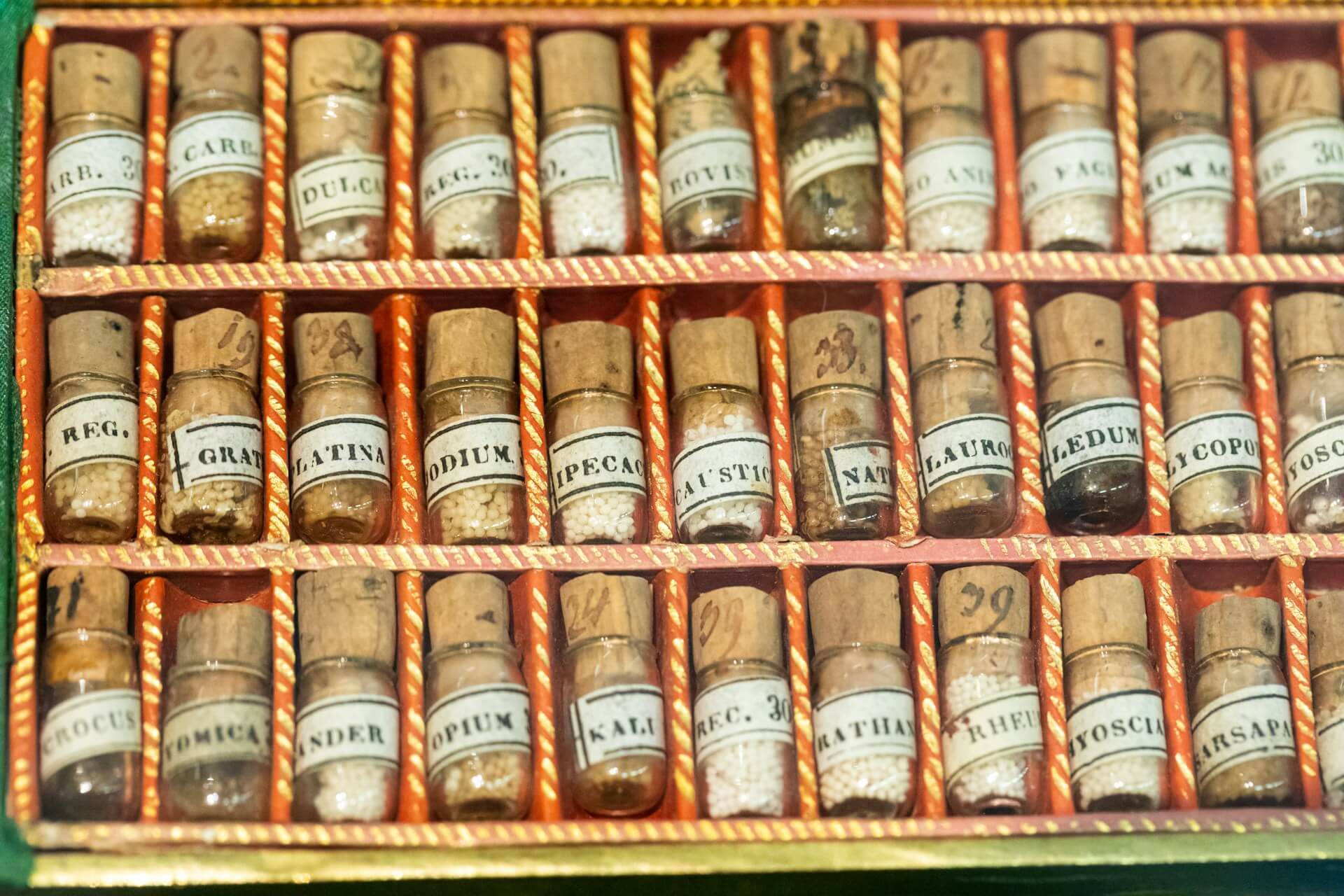 Brown shelf full of homeopathic medicine bottles.